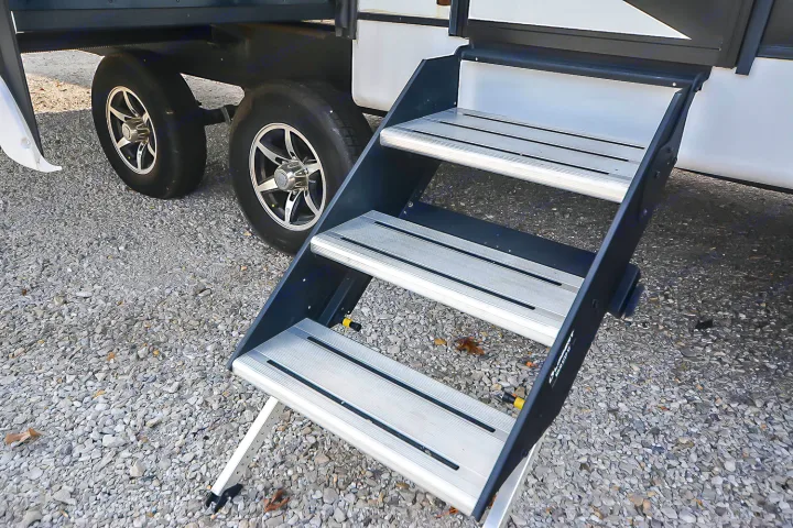 Sturdy RV rental entry steps extend to gravel. Shows multi-tiered steps & dual tires for easy access to your travel trailer.. Coachmen Coachmen Freedom Express Liberty Edition (324RLDSLE) 2022