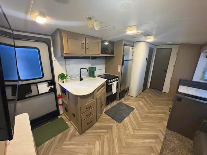 Explore this RV rental's modern interior: a full kitchen with island, appliances, and stylish herringbone flooring. Ideal for trips.. Cruiser RV Shadow Cruiser 2021