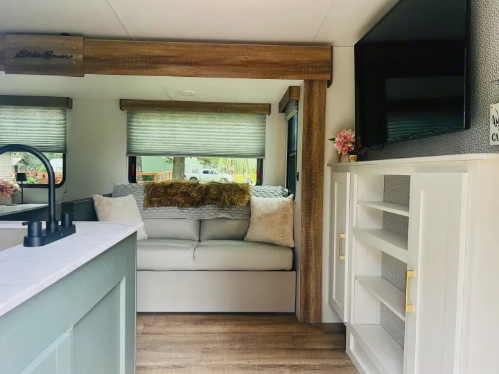 Bright Eddie Bauer RV rental interior: modern living area with light sofa, mounted TV, and wood-look accents.. Heartland RVs 265BH-L 2024
