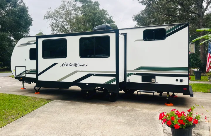 This Eddie Bauer RV rental, stabilized with jacks, showcases its extended slide-outs on a concrete driveway, ready for adventure.. Heartland RVs 265BH-L 2024