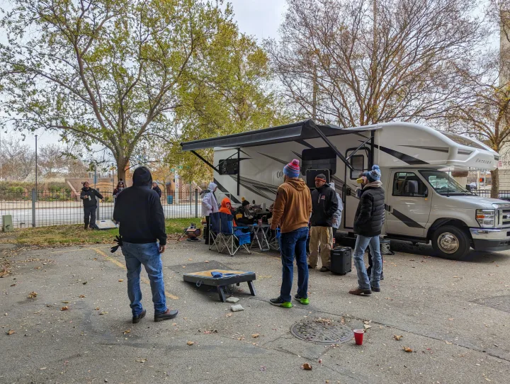 Friends tailgate with an RV rental, playing cornhole and socializing outdoors on an autumn day.. Entegra Coach Odyssey 2024