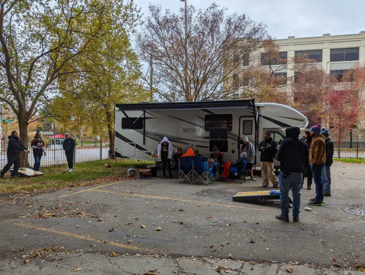 People gathered around an Odyssey RV rental, tailgating, playing cornhole, and enjoying the outdoors on a fall afternoon.. Entegra Coach Odyssey 2024