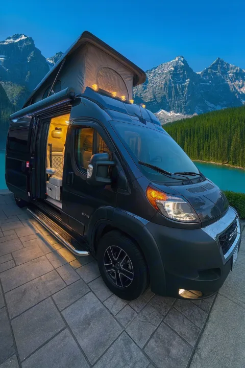 Explore nature's beauty in this RV rental camper van with pop-top roof. Illuminated interior at a stunning mountain lake.. Jayco Swift 2023