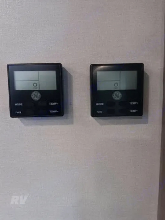 Two GE digital thermostats on a wall in an RV rental, providing essential temperature and fan control for comfort.. Other Catalina 2025