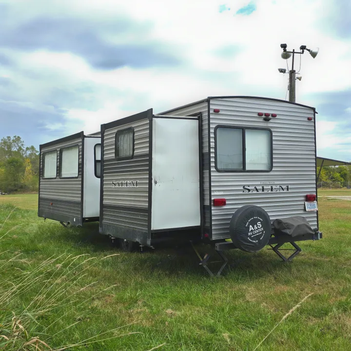 This Forest River Salem travel trailer, an RV rental from A&S RV Center, is parked in a grassy field with slide-outs extended.. Forest River Salem 2019