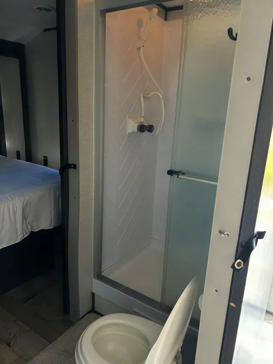 RV rental: Compact bathroom with a herringbone-patterned shower, toilet, and a peek into the adjacent bedroom.. Dutchmen 3120BHS 2021