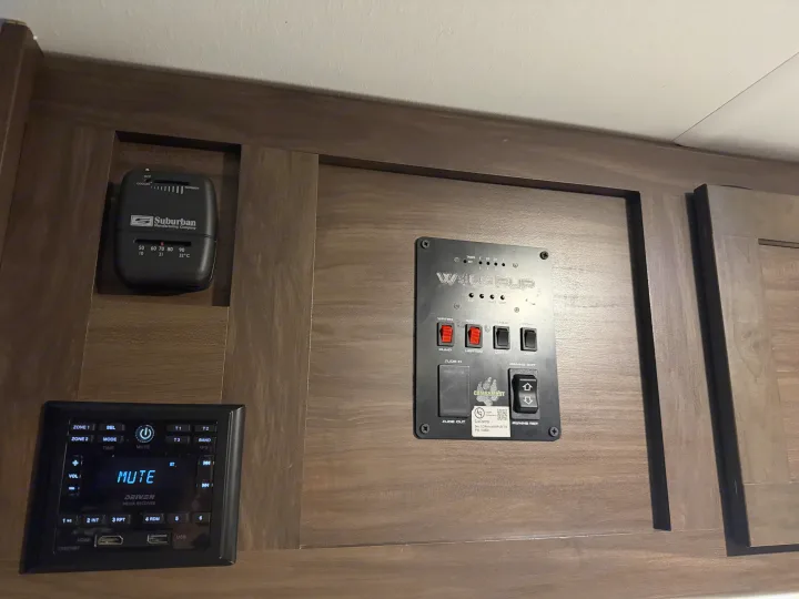 RV rental control panel: thermostat, water/tank monitors, awning/slideout controls, and a Bluetooth media player.. Forest River Cherokee Wolf Pup 2021