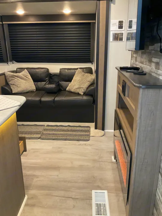 This inviting RV rental features a comfortable leather couch, stylish fireplace, and modern interior design.. Keystone RV Hideout 2021