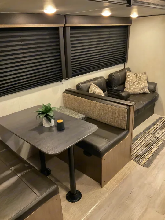 RV rental interior featuring a modern dark dinette and comfy leatherette sofa with stylish decor.. Keystone RV Hideout 2021