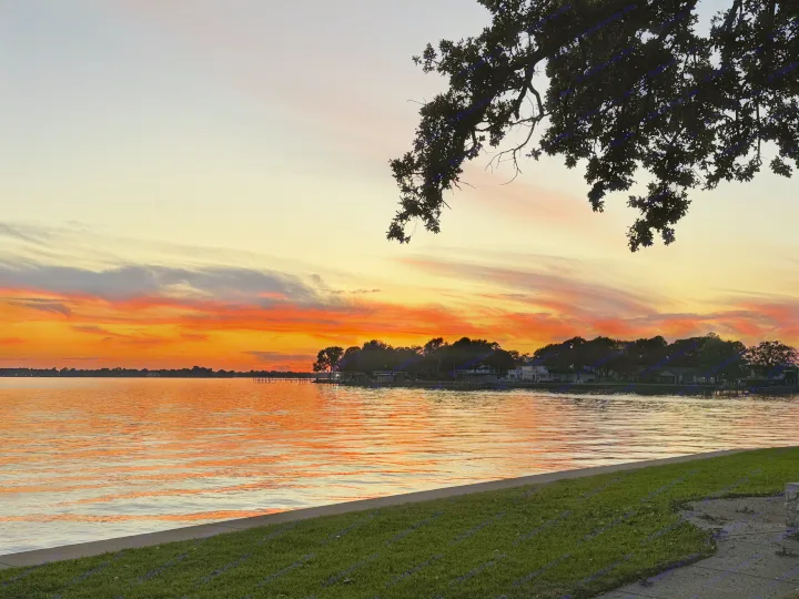 Fiery sunset over a tranquil lake, ideal for RV rental getaways. Enjoy the vibrant sky & water reflections.. Winnebago Revel 2025