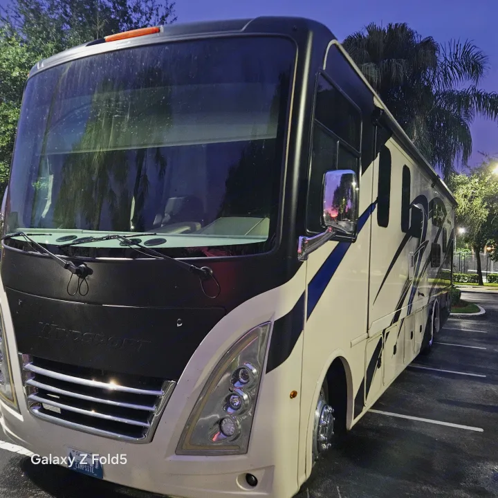 Front of a large, cream and black Thor Windsport RV rental at dusk, parked under palm trees. Ready for your travel adventures.. Thor Windsport 2023