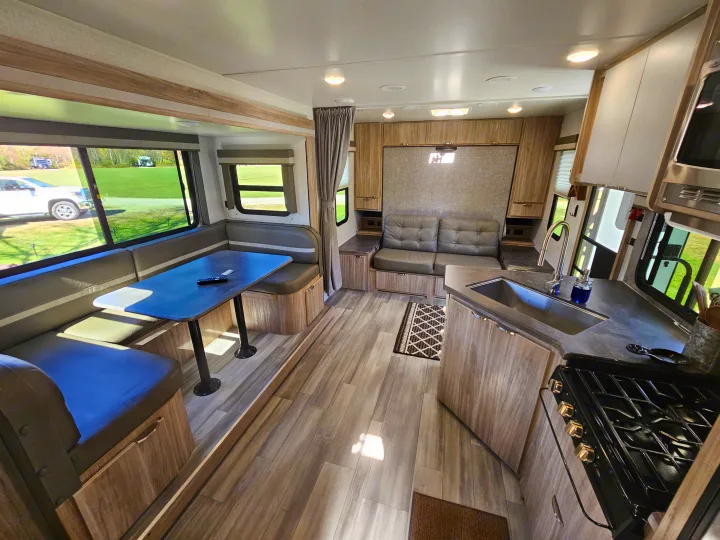 Step inside this inviting RV rental: dinette, kitchen, & sofa by a murphy bed. Bright, modern travel living space.. Winnebago Minnie 2201MB 2022