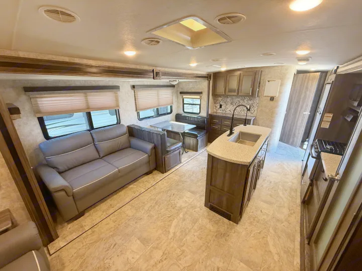 Spacious, modern RV rental interior with living area, kitchen island, and dining booth.. Highland Ridge RV Light 2018