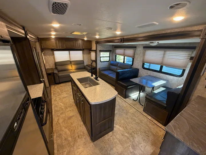 This spacious rv rental showcases its modern interior with a kitchen island, comfortable sofas, and a cozy dinette setup.. Highland Ridge RV Light 2018
