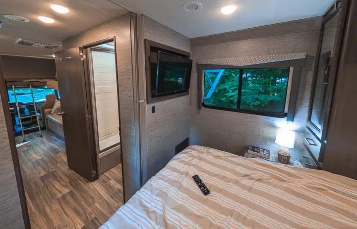 Experience the comfort of this modern RV rental's bedroom, living area, and full bathroom, ideal for adventurous travel.. Thor Four Winds 2021