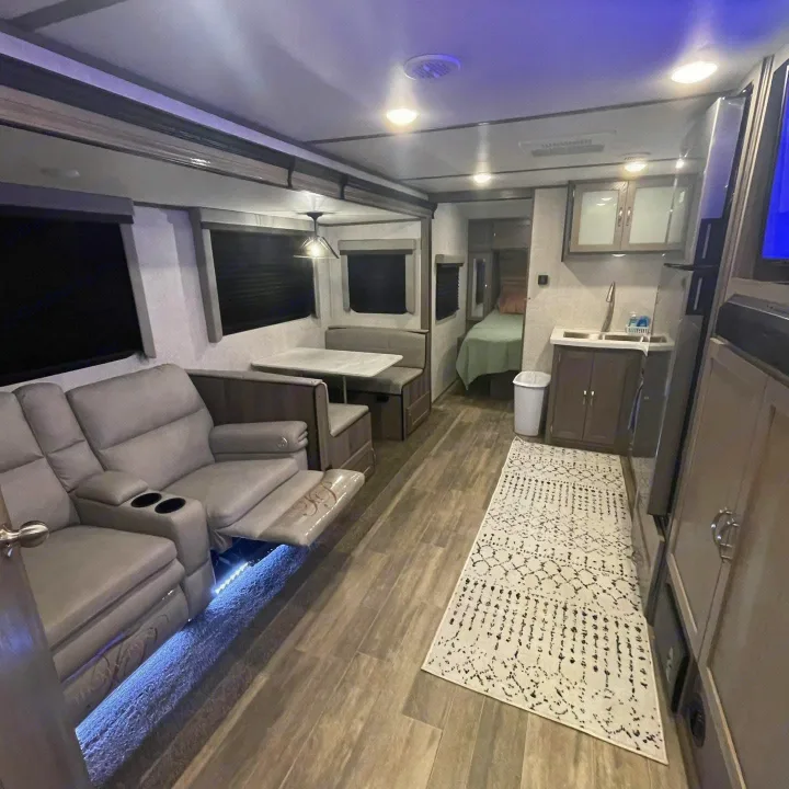 Spacious RV rental interior featuring recliners, dinette, kitchenette, and bedroom area. Modern design with wood floors and accent lighting.. Gulf Stream Envision 2023
