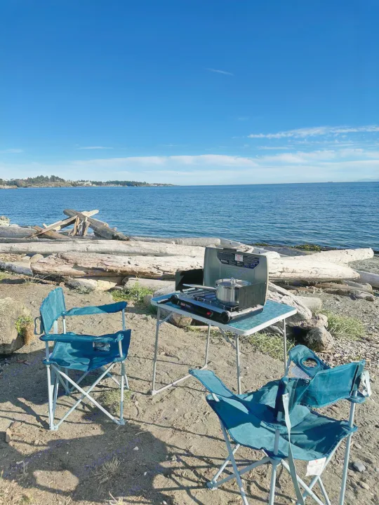 Perfect RV rental day! Beachside camp kitchen with stove, pot, chairs, by tranquil ocean and clear blue sky.. Gmc Savanna 2003