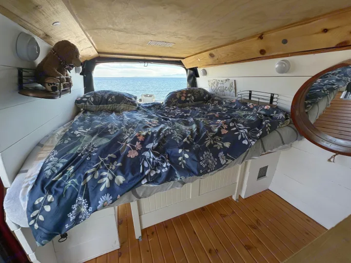 Experience van life in this cozy RV rental bedroom. Wake up to ocean views from your comfortable floral bed.. Gmc Savanna 2003