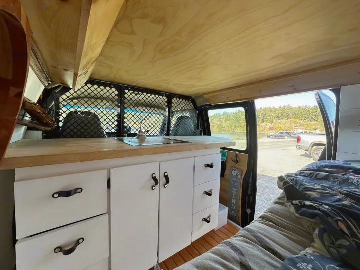 Cozy RV rental interior: Custom camper van with kitchen, bed, & scenic water views. Perfect for van life adventures!. Gmc Savanna 2003