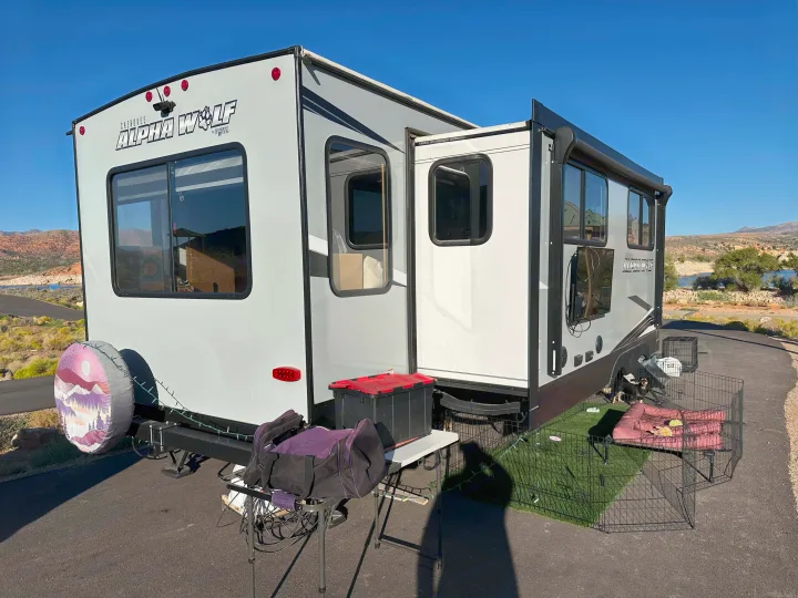 This RV rental is parked with an outdoor pet enclosure, offering a scenic view of mountains and a lake in the distance.. Forest River Cherokee Alpha Wolf 2021