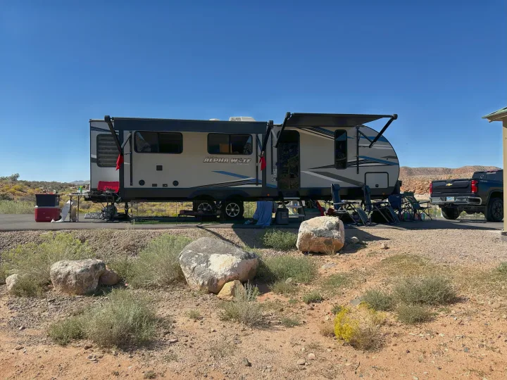 This **RV rental**, an Alpha Wolf travel trailer, is set up for desert camping with an outdoor living area and a pickup truck nearby.. Forest River Cherokee Alpha Wolf 2021