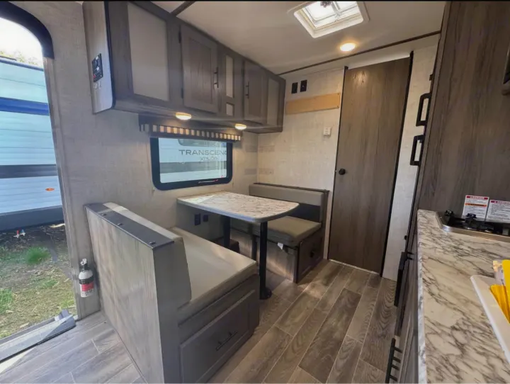 Modern RV rental interior showcasing a functional dinette, well-equipped kitchen area, and overhead storage cabinets.. Gulf Stream Kingsport Super Lite 2021