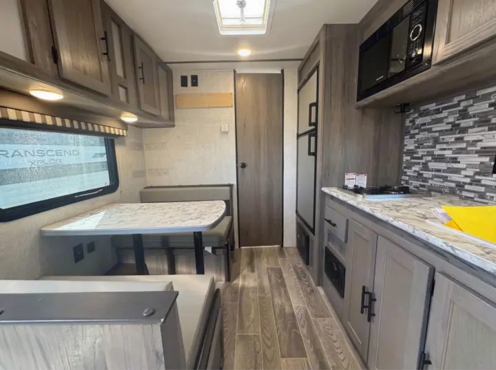 RV rental interior features a compact kitchen with microwave, stove, and a comfortable dinette with seating, all in a modern design.. Gulf Stream Kingsport Super Lite 2021
