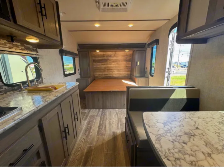 RV rental interior: kitchen with marble counters, convertible bed/dinette area, and a dining space with booth seating.. Gulf Stream Kingsport Super Lite 2021