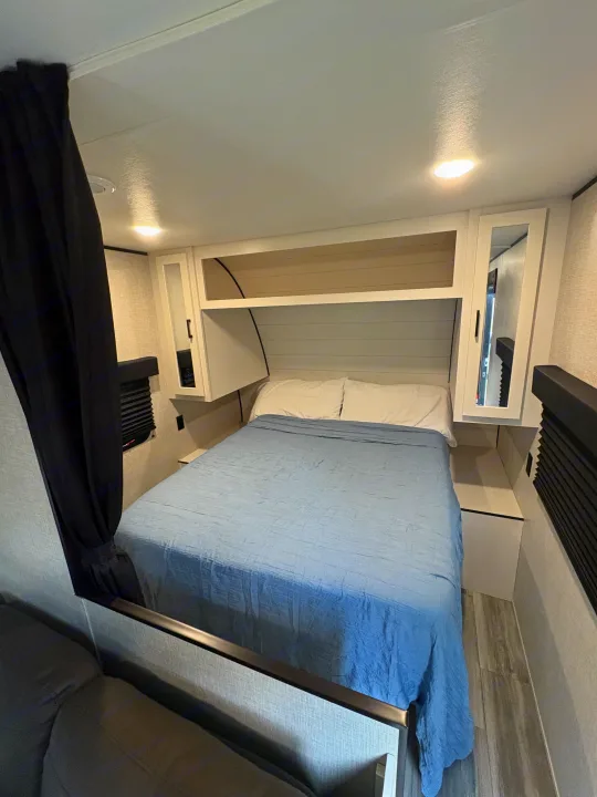 Modern RV rental bedroom featuring a cozy bed, white pillows, overhead storage, and ceiling lights. Ideal for travel comfort.. Jayco Jay Flight SLX 2024