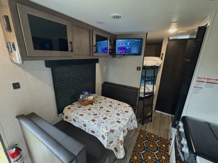 Cozy RV rental interior: dinette with S'mores setup, bunk beds, kitchen, & multiple TVs for a fun family trip.. Jayco Jay Flight SLX 2024