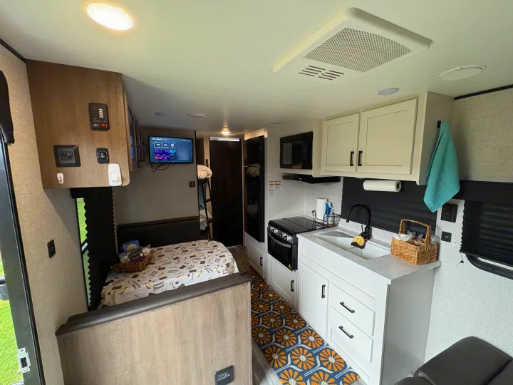 This RV rental features a modern kitchen, a comfy dinette with a "S'more Please!" blanket, and bunk beds.. Jayco Jay Flight SLX 2024