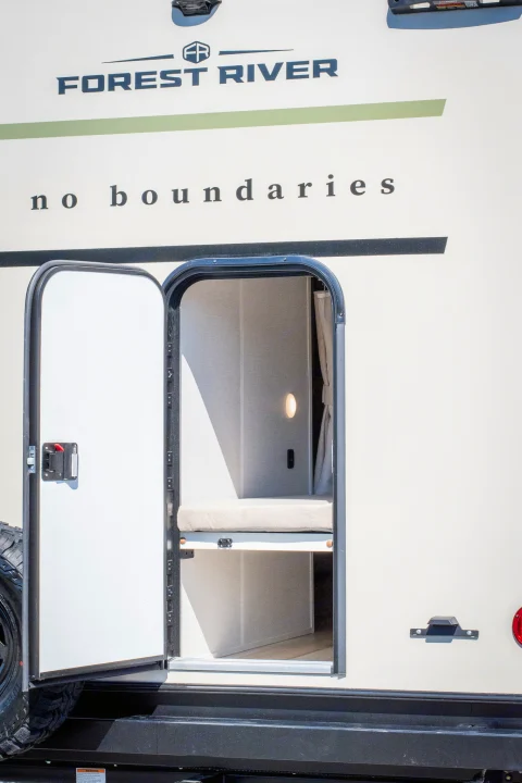 Open door of a Forest River No Boundaries RV rental reveals a cozy bunk area with an interior light. Ideal for adventure!. Forest River No Boundaries 2026