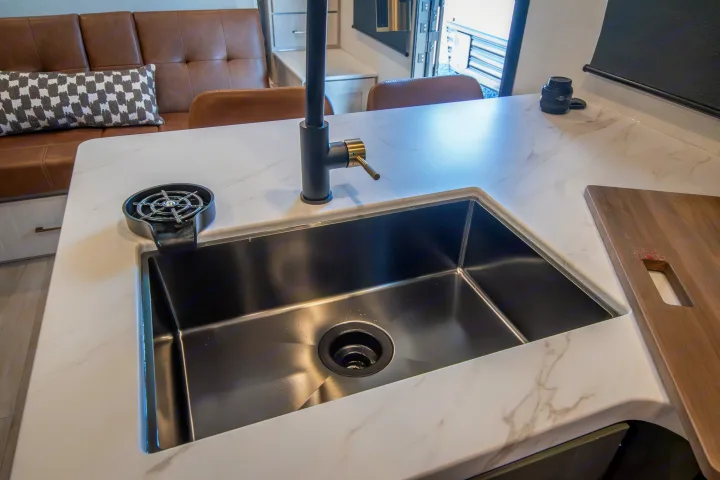 Stylish RV rental kitchen featuring a deep black sink, modern faucet, glass rinser, and veined white counter.. Forest River No Boundaries 2026