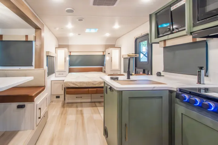 A bright, modern rv rental interior with a green kitchen, dining booth, and cozy bedroom, ready for your next adventure.. Forest River No Boundaries 2026