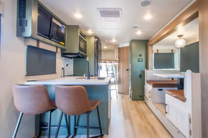 Modern RV rental interior featuring a green kitchen, bar seating, and a dining booth, ideal for comfortable travel.. Forest River No Boundaries 2026