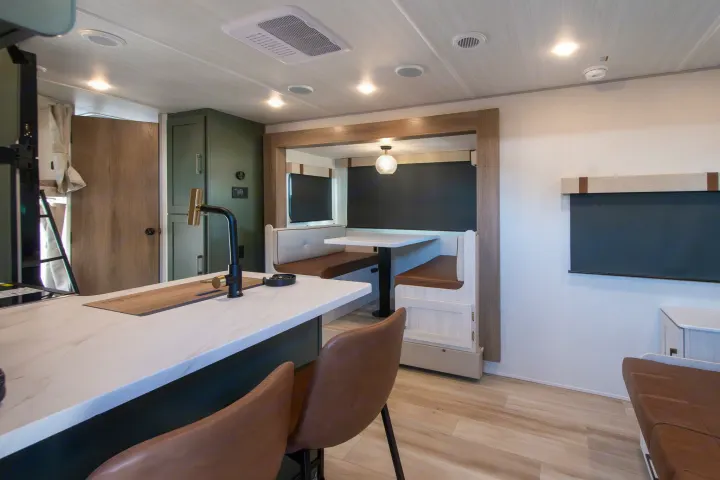 Explore this modern RV rental interior featuring a kitchen island, dining booth, and clean, contemporary design.. Forest River No Boundaries 2026