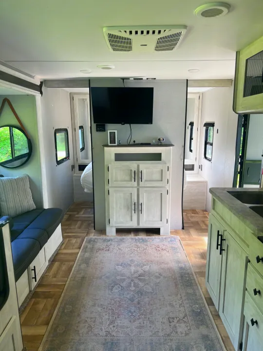 Modern RV rental interior: inviting sofa, central entertainment, kitchen, and rear bedroom hallway with wood floors.. Forest River Shasta 2022