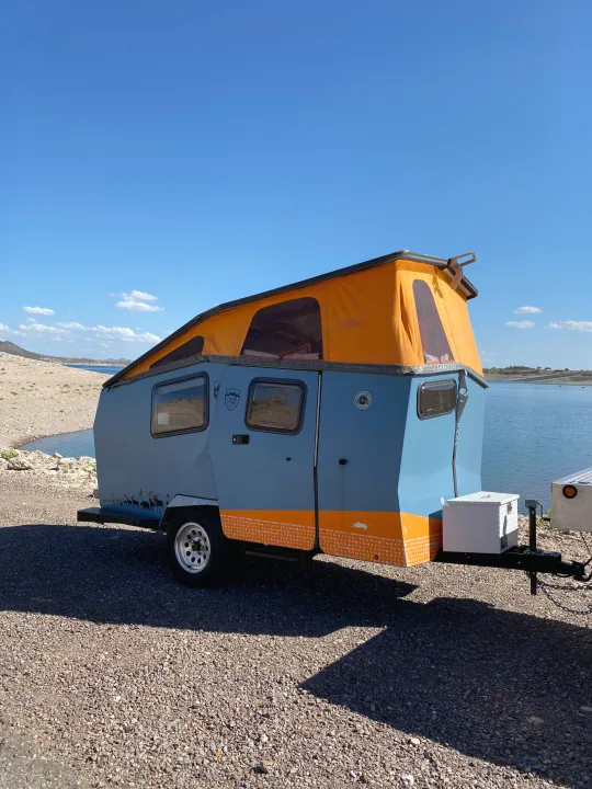 Lakeside RV rental: a stylish blue Cricket camper with an orange pop-top tent, perfect for outdoor adventures.. Cricket standard 2013