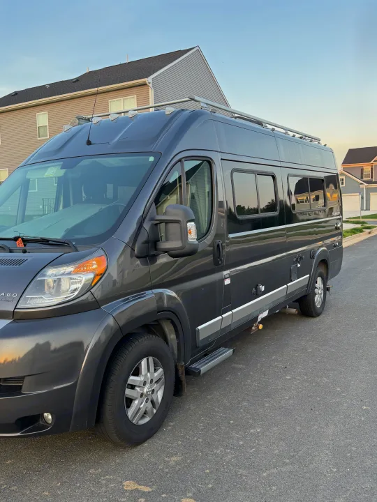 Dark grey Winnebago camper van, perfect for rv rental getaways, parked on a quiet residential street in soft evening light.. Winnebago Travato 2016