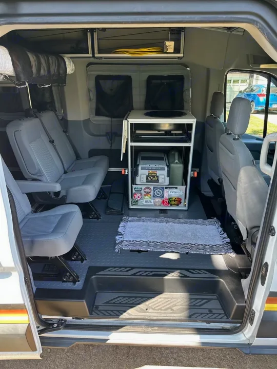 RV rental interior: organized camper van with compact kitchen, flexible seating, and overhead storage for mobile living.. Ford Transit 2018
