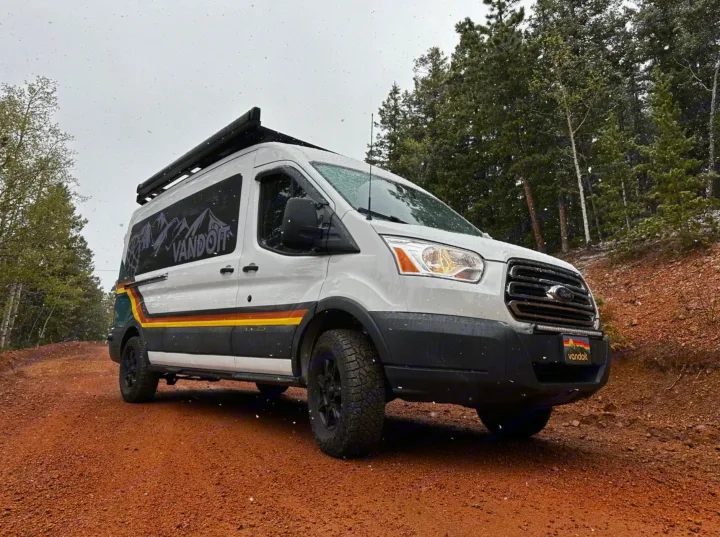 Adventure-ready Ford Transit camper van on a snowy dirt road. Perfect for your next RV rental exploration. Vandoit branded.. Ford Transit 2018