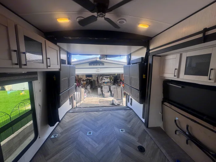 RV rental interior: A toy hauler's versatile cargo area with an open rear ramp leading to a garage. Ceiling fan, cabinets.. Heartland Torque 2022