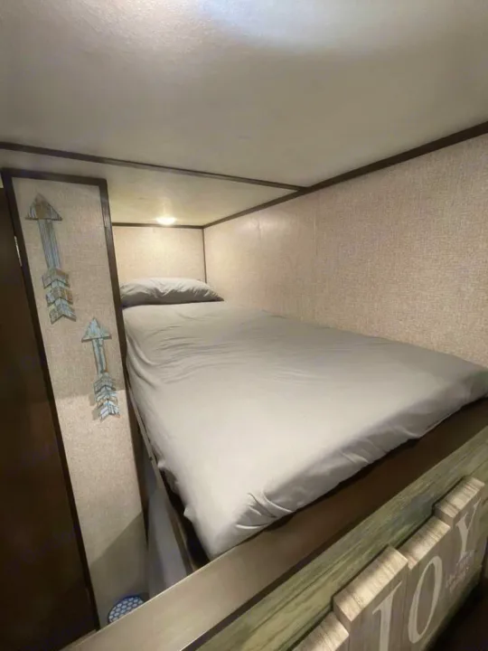 Comfortable sleeping area in an RV rental, featuring a cozy bed with grey sheets and decorative wall art.. LANTERN 17B 2021