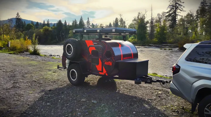 An off-road teardrop trailer, ideal for an RV rental, parked by a river in a scenic mountain setting.. Teardrops NW Ranger 2025