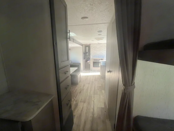 RV rental interior: View down the hallway showing a modern dinette, kitchen, and bunk area with wood-look flooring.. Dutchmen Coleman Lantern 2022