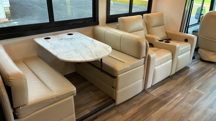 Modern RV rental interior featuring a cream-colored dinette with a marble-look table and comfortable reclining chairs.. Jayce Precept G 2026