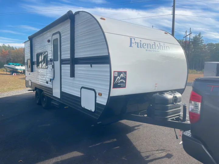 White Gulf Stream Friendship travel trailer for rv rental from Adventure Camper Rentals, hitched to a truck on an asphalt lot.. Gulf Stream Friendship 2022