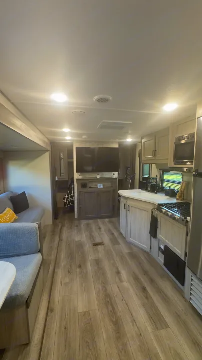 Bright & modern RV rental interior featuring a kitchen, living area with couch, and TV, offering a spacious feel.. Coachmen Catalina 2025