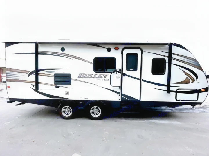 This white Bullet Ultra Lite travel trailer, seen from the side, is available for RV rental. Features sleek graphics and multiple windows.. Keystone RV Bullet Ultra Lite 2014