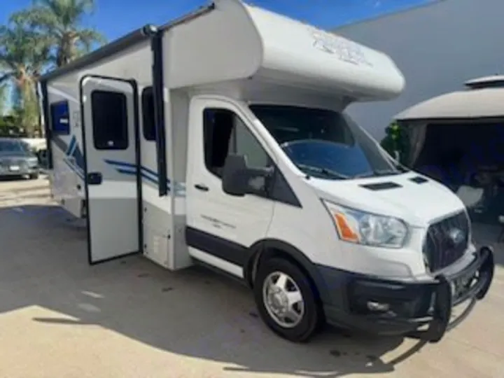 This white and grey Class C rv rental, with an extended awning, open door, and front bull bar, is ready for travel.. Forest River Coachmen Cross Trek 2021